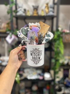 a person holding up a coffee mug with witches brew in it