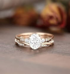 a close up view of a diamond engagement ring on a wooden table with flowers in the background