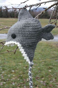 a crocheted shark hat hanging from a tree branch