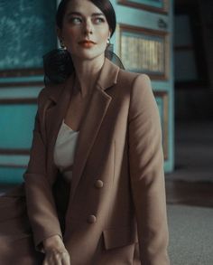 a woman is sitting on the floor in a suit and heels with her hand on her hip