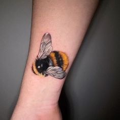 a small tattoo of a bee on the left inner arm, with yellow and black stripes