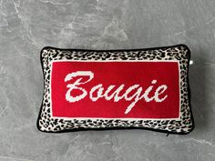 a red and white pillow with the word bougie in leopard print on it