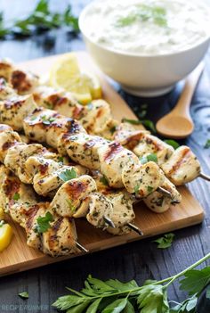 grilled chicken skewers on a wooden cutting board with lemon wedges