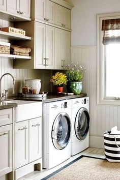 a washer and dryer in a small room next to a window with flowers