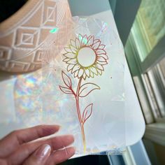 a person holding a flower in front of a glass plate with the image of a sunflower on it