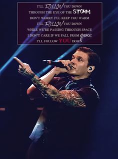 a man with tattoos on his arm holding a microphone in front of a sign that says, i'll tell you down