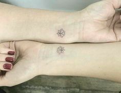 two women with matching tattoos on their arms, both holding each other's hands