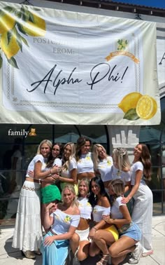 a group of women standing next to each other in front of a lemon advertisement banner