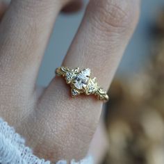 a close up of a person's hand wearing a gold ring with three stones