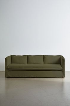 a green couch sitting on top of a hard wood floor