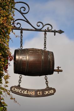 a sign hanging from the side of a building with a wooden barrel attached to it