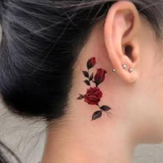 a woman's behind the ear tattoo with red roses