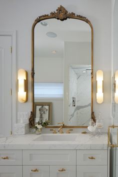 a bathroom vanity with a large mirror above it and lights on either side of the sink