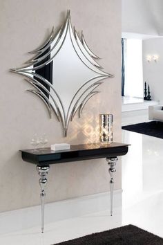 a mirror on the wall above a console table in a room with black and white decor