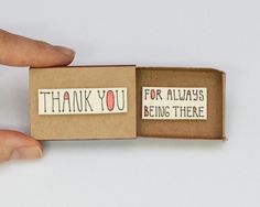 a hand holding an open box with some type of thank you stickers on it