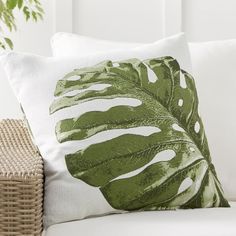 a white couch with a green leaf pillow on it