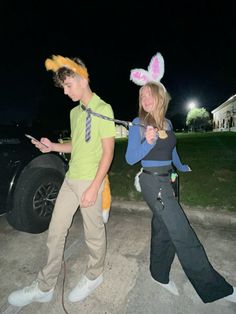 two people in bunny ears are standing next to a car and one person is using a cell phone