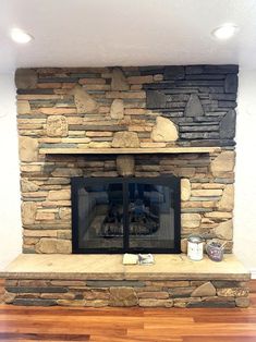 a stone fireplace in a living room with wood floors