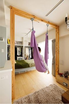 a woman is sitting in a hammock hanging from the ceiling above her bed