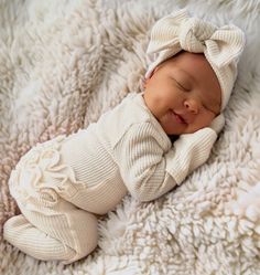 a baby sleeping on top of a blanket wearing a white bowknotd hat