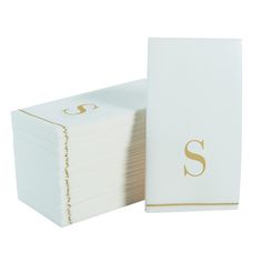 a stack of white napkins with the letter s printed on it and gold trimming