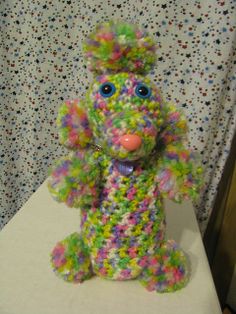 a multicolored stuffed animal sitting on top of a white table next to a wall