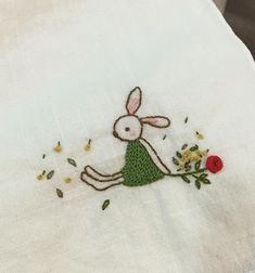 an embroidered rabbit sitting on top of a white table cloth