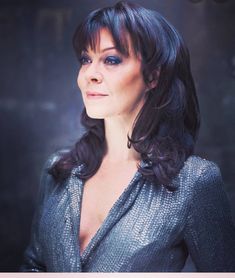 a woman with dark hair wearing a silver dress