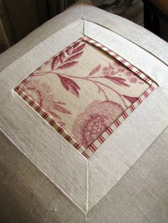 a close up of a table cloth with a flower design on it and a small square in the middle