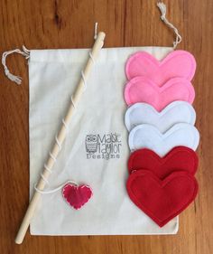 four heart shaped felts are on a white bag with a wooden stick and thread