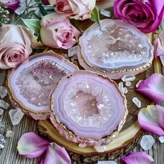 three pink agate slices sitting on top of a piece of wood next to flowers