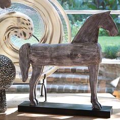 a wooden horse statue sitting on top of a table next to a vase and bowl