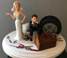 a wedding cake topper with a bride and groom sitting on the back of a car