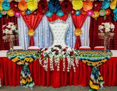 a decorated banquet table with red, yellow and blue flowers on the headpieces