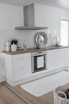 a kitchen with white walls and wooden floors, including a stove top oven in the center