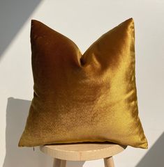 a gold pillow sitting on top of a wooden stool