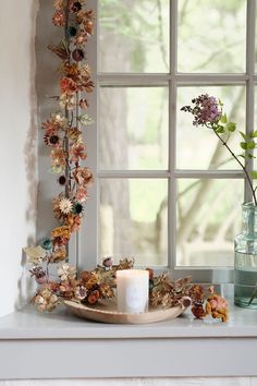 a window sill with flowers and candles on it