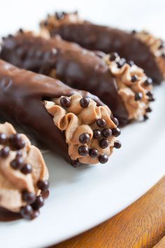 three chocolate covered donuts on a white plate