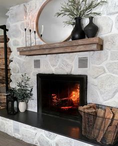 a fireplace with a fire in it next to a mirror and potted plant on the mantle