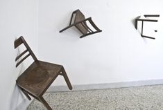 two wooden chairs sitting next to each other in front of a wall with hooks on it