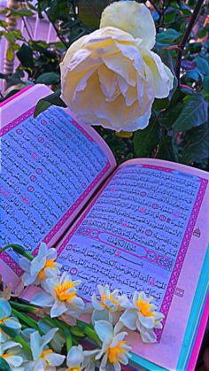 an open book sitting on top of a table next to flowers