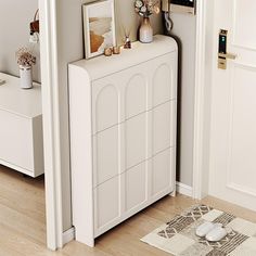 a white dresser sitting next to a doorway with pictures on the top and below it