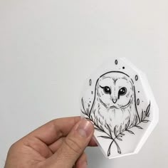 a hand holding an ornament with an owl drawn on it's face