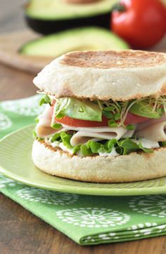 a sandwich with lettuce, tomato, and cheese on it sitting on a green plate