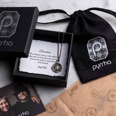 two personalized necklaces are in a gift bag and one has a photo on it