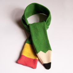 a green scarf with a pencil sticking out of it's end on a white surface