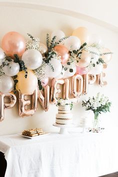 a table topped with balloons and cake next to a wall