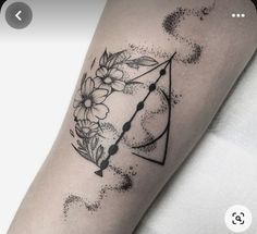 a woman's arm with a flower and arrow tattoo on it