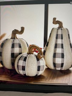 three decorative pumpkins sitting on top of a wooden table