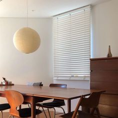 a dining room table with four chairs and a lamp hanging from the ceiling over it